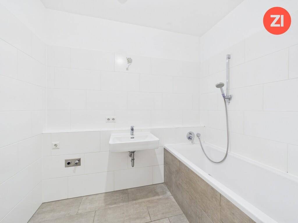 Modernes Badezimmer mit Badewanne, weiß gefliesten Wänden und einem einzelnen Waschbecken.