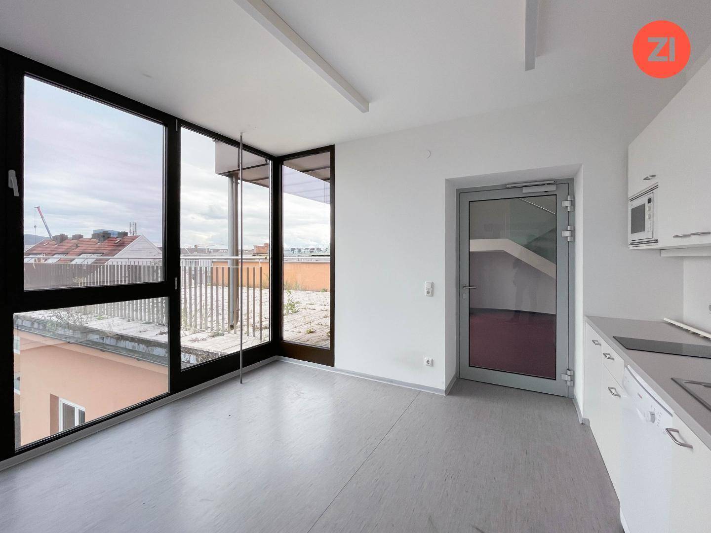 Helle Küche mit Einbauschränken, großen Fenstern und Zugang zu einem Balkon.