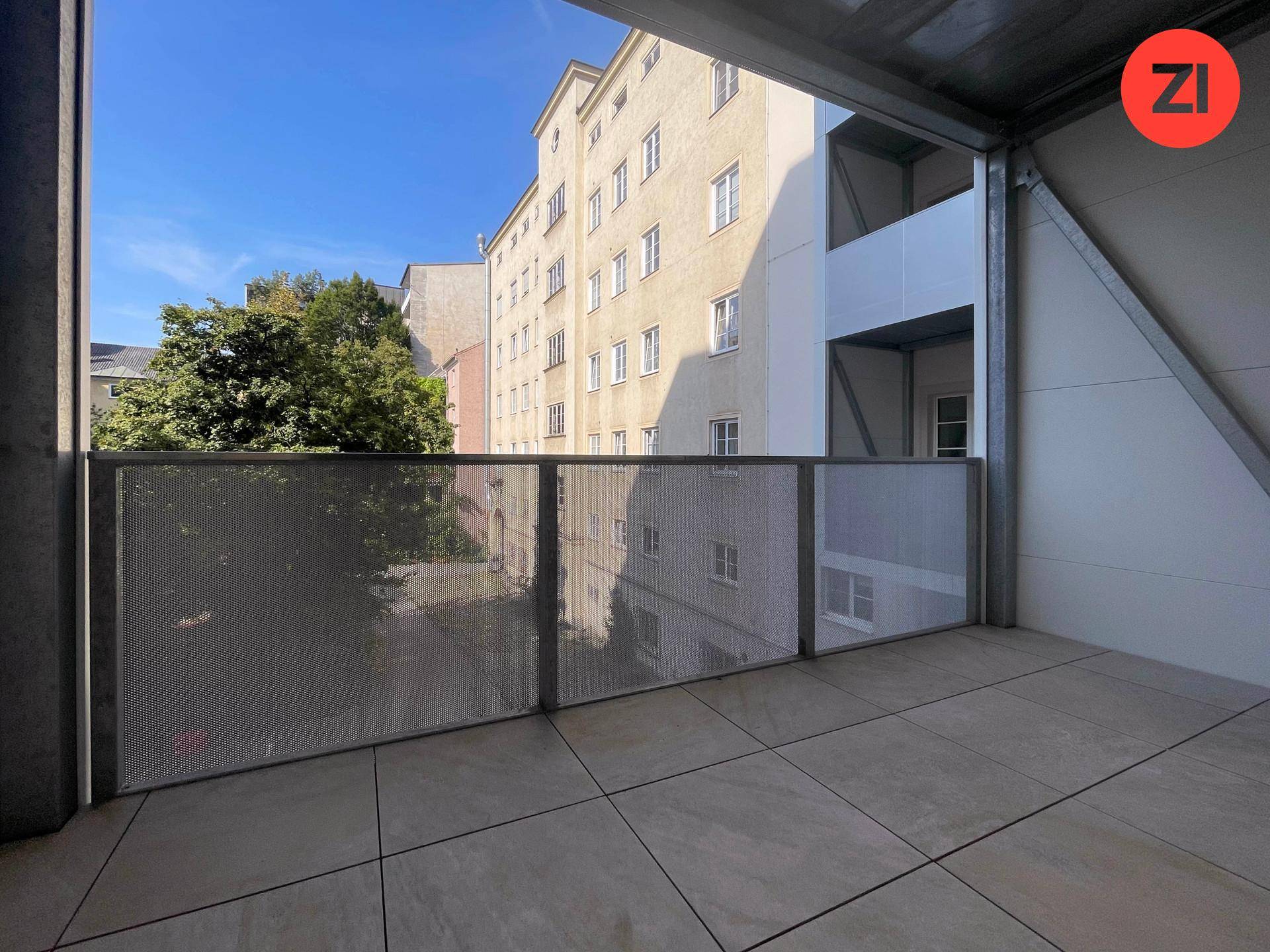 Moderner Balkon mit Fliesenboden und Metallgeländer, bietet einen Blick auf die städtische Umgebung.