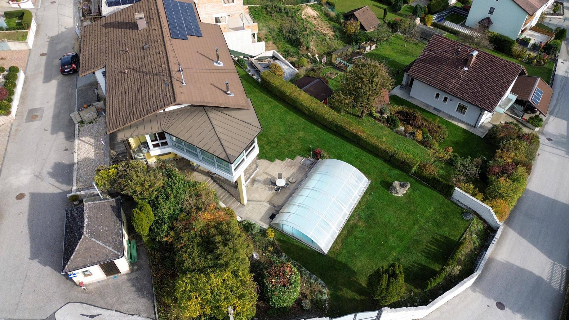 Luftaufnahme des Anwesens mit großem Garten, Pool und umliegender Wohnsiedlung.