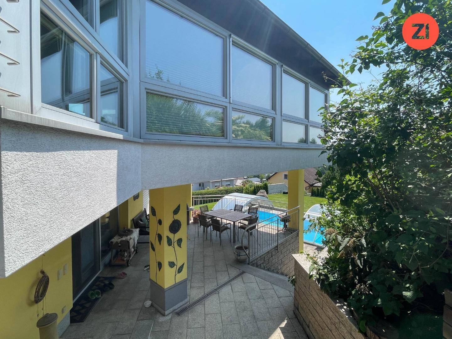 Überdachte Terrasse mit Essbereich und Blick auf den Pool und die umliegende Landschaft.