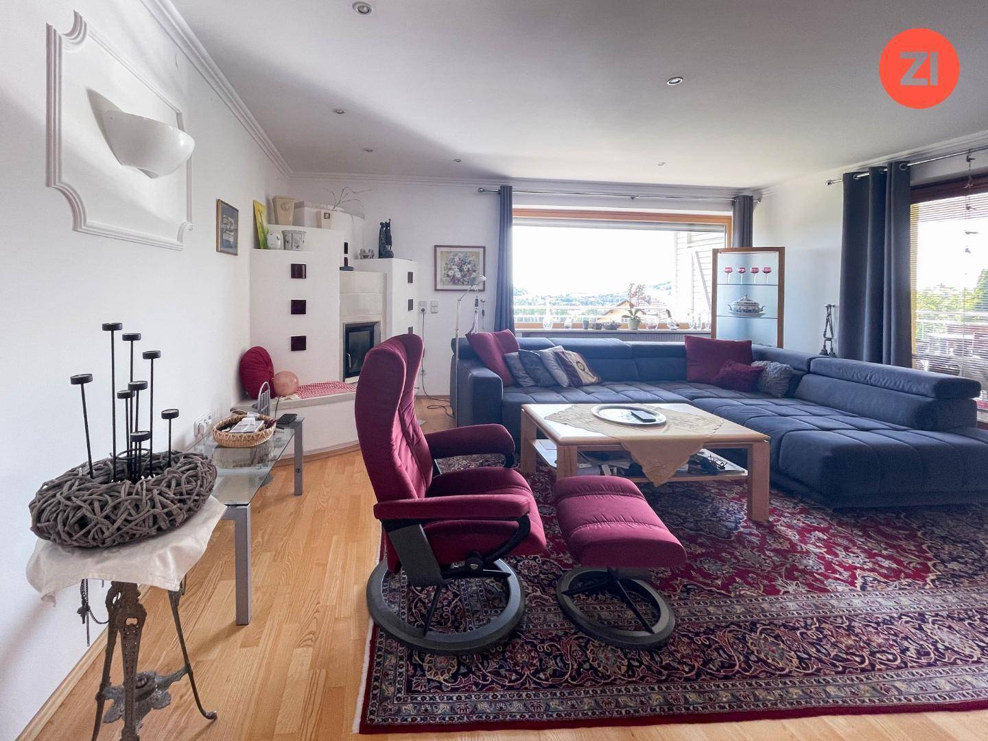 Geräumiges Wohnzimmer mit Holzboden, großem Sofa und traditionellem Kachelofen.