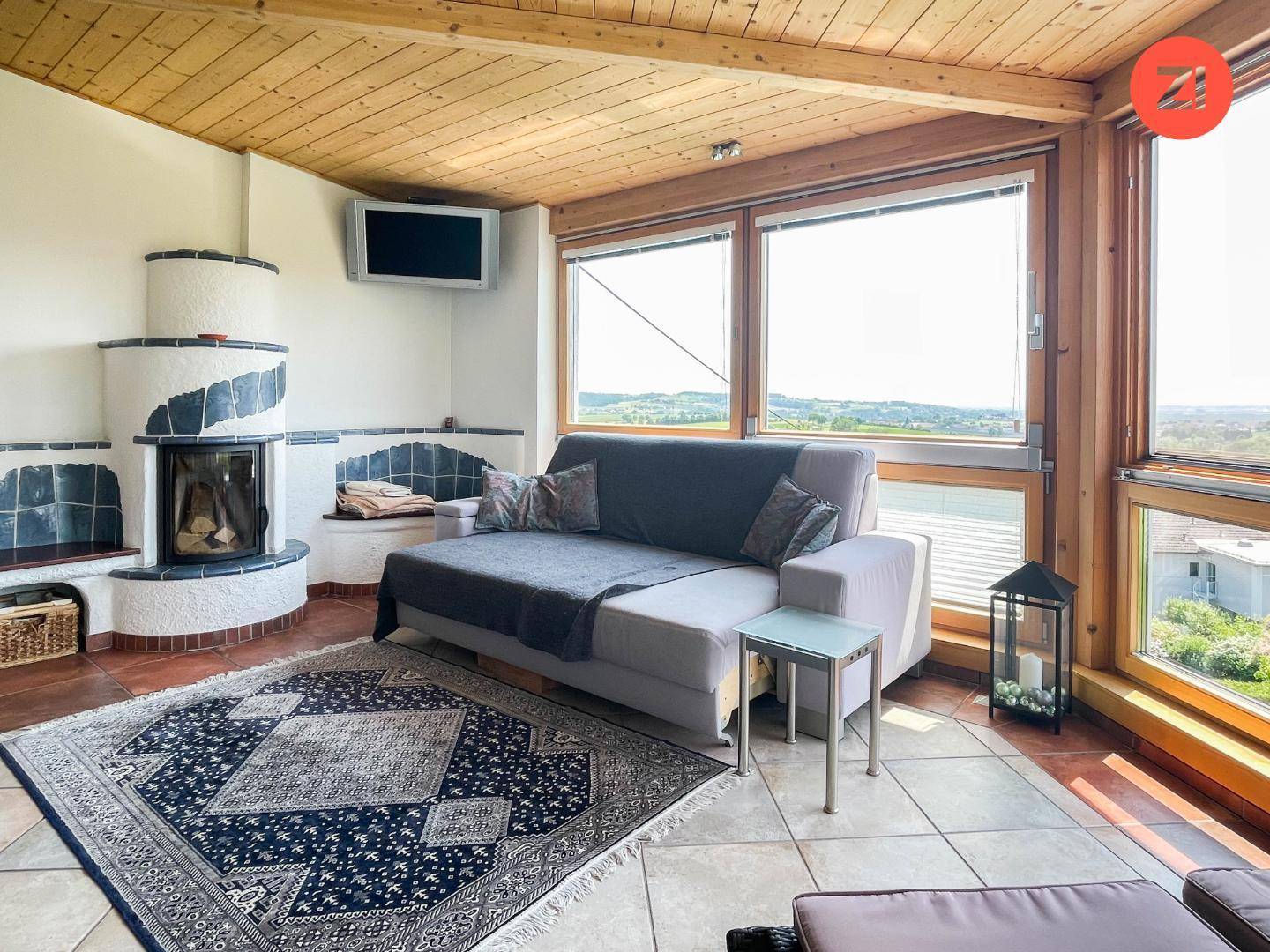Gemütlicher Wintergarten mit Kamin, bequemer Couch und Panoramablick auf die Umgebung.
