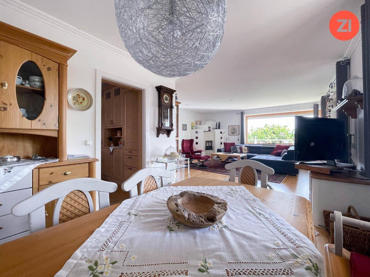 Gemütlicher Essbereich mit Holztisch und Blick in das angrenzende Wohnzimmer mit Kachelofen.