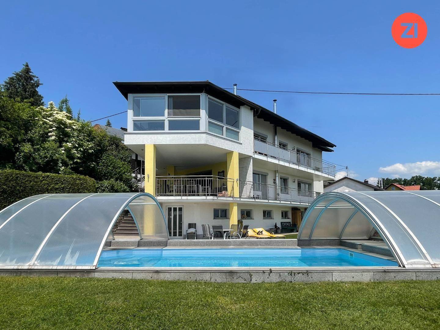 Ansicht des Hauses von der Gartenseite mit großem Pool und überdachter Terrasse.