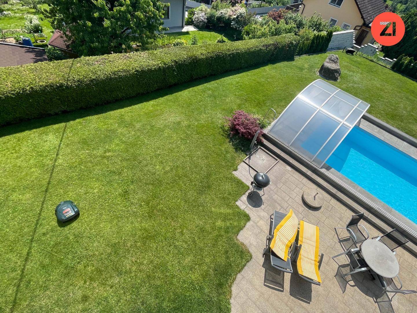 Gepflegter Gartenbereich mit Rasen, Pool und Liegestühlen für Entspannung im Freien.