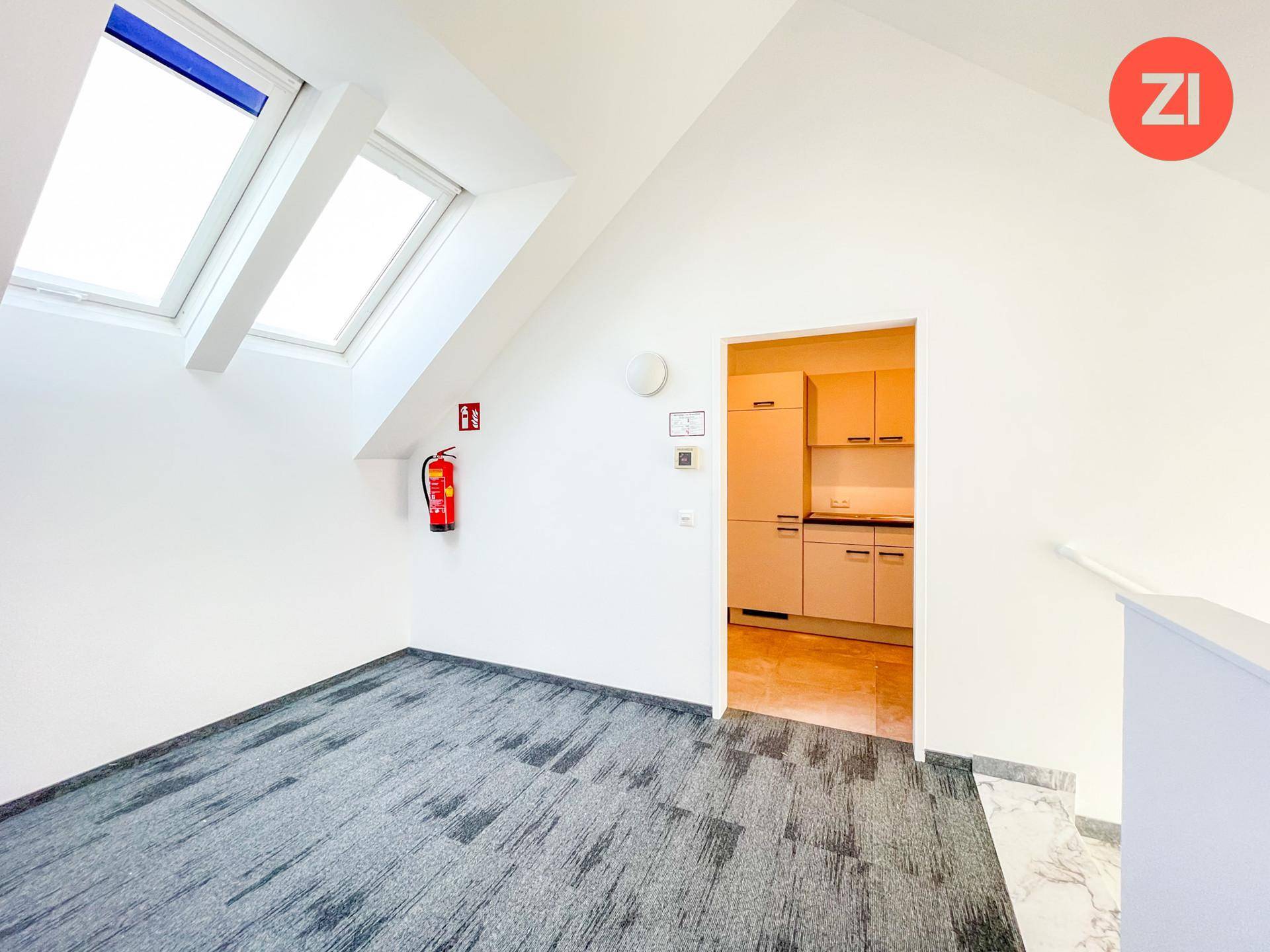 Flur mit Teppichboden und Zugang zu einer kleinen Küche, beleuchtet durch Dachfenster.
