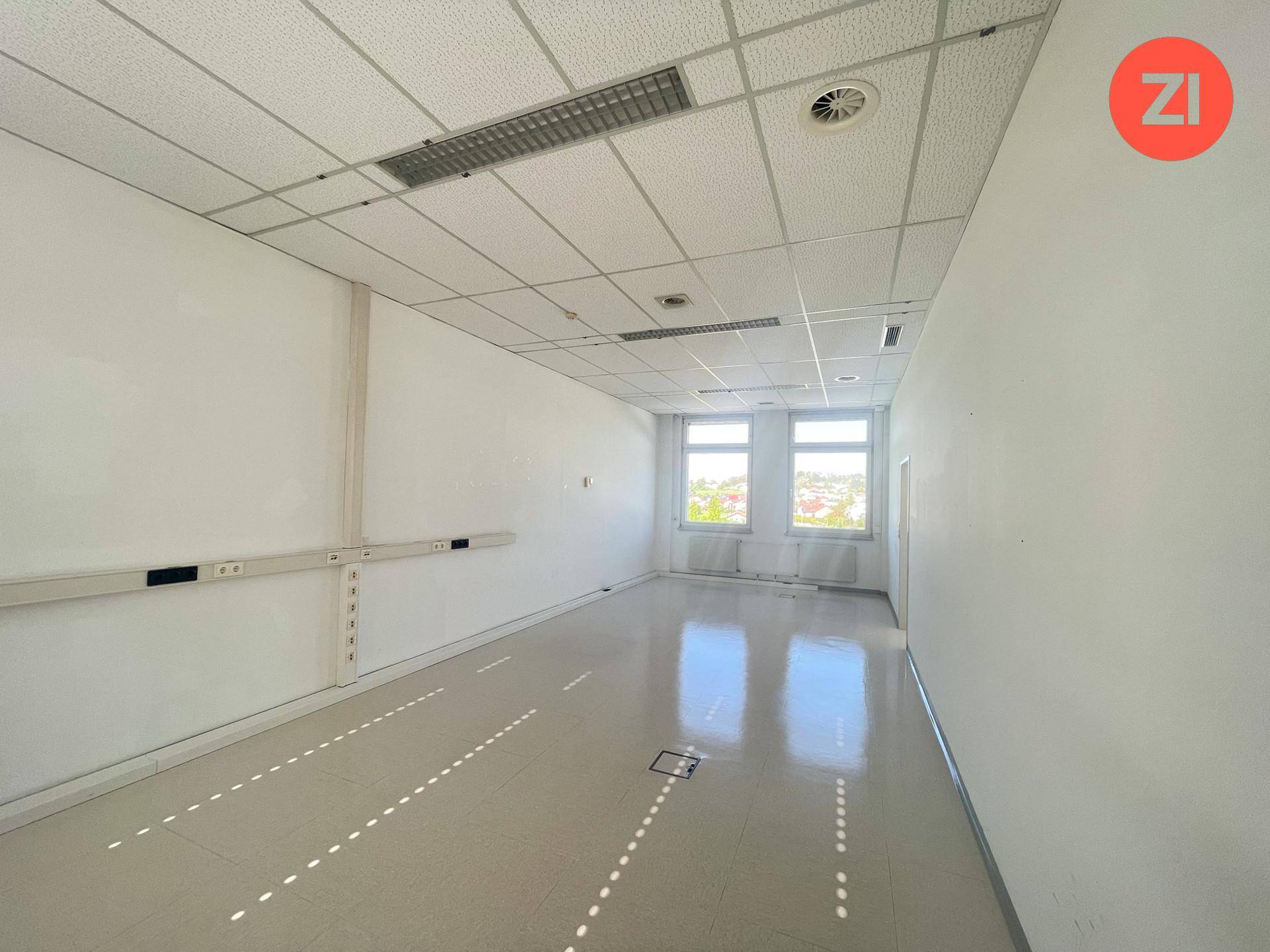Weiterer Blick in einen leeren Büroraum mit zwei Fenstern und einer weiten Aussicht.