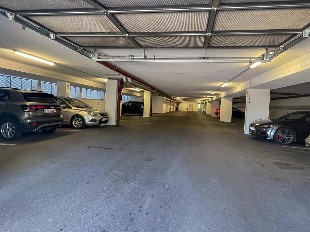 Geräumige Tiefgarage mit mehreren geparkten Fahrzeugen und heller Beleuchtung.