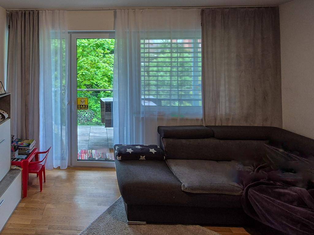 Gemütliches Wohnzimmer mit großem Sofa, Holzboden und Zugang zu einer Terrasse mit Grünblick.