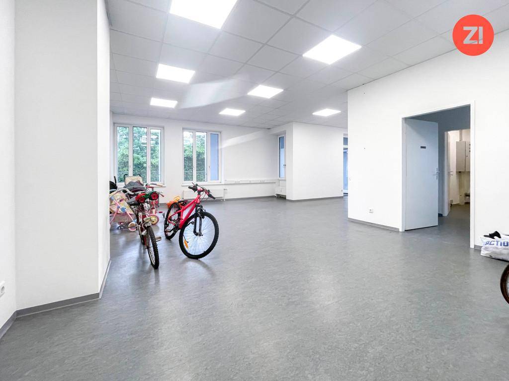 Heller, offener Bürobereich mit mehreren Fenstern und grauem Bodenbelag, teilweise mit Fahrrädern.