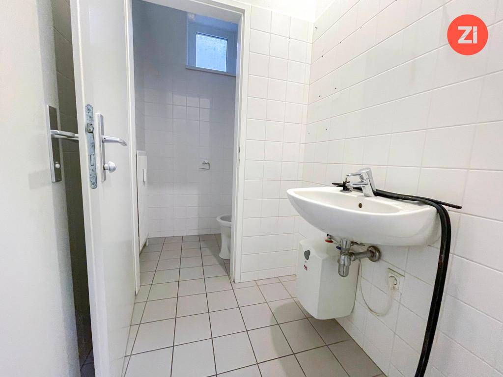 Badezimmer mit Waschbecken, Boiler und Zugang zu einem separaten WC-Bereich.