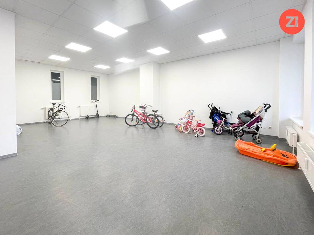 Geräumiger Abstellraum mit Fahrrädern, Kinderwagen und Spielzeug auf grauem Vinylboden.