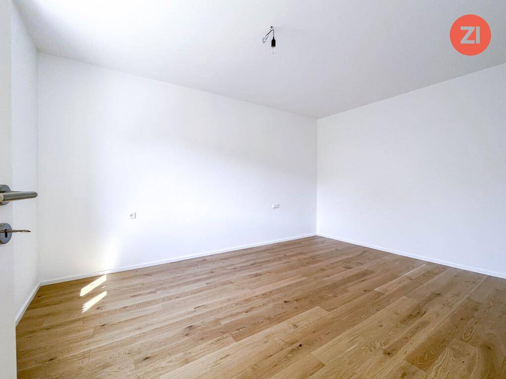 Heller, leerer Raum mit Holzfußboden und weißen Wänden, bereit zur individuellen Gestaltung.