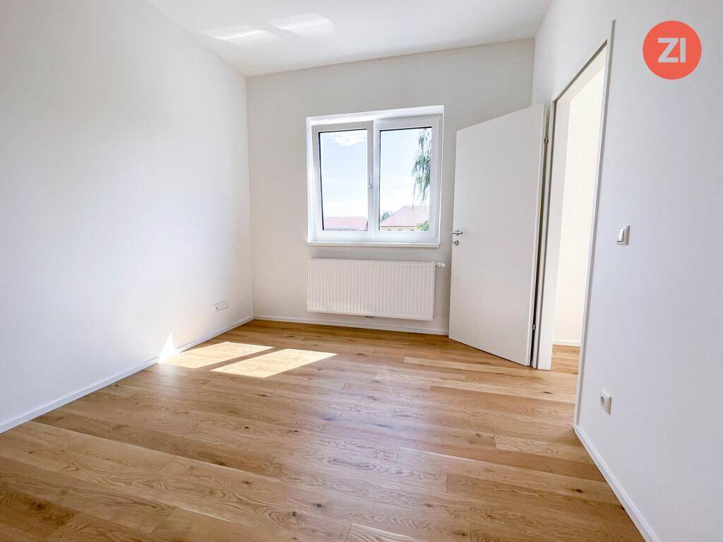 Freundliches Zimmer mit Parkettboden und einem Fenster, das viel Sonnenlicht in den Raum bringt.
