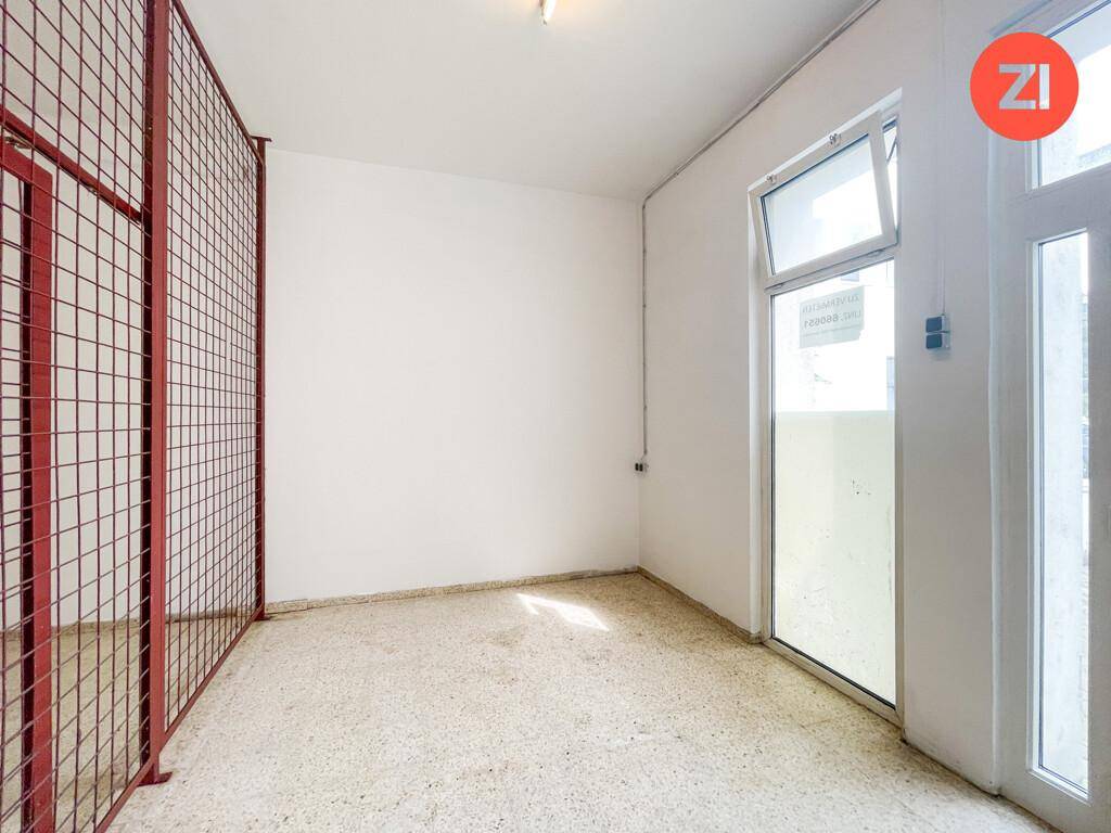 Heller Lagerraum mit Gitterabtrennung, großem Fenster und einfachem Betonboden.