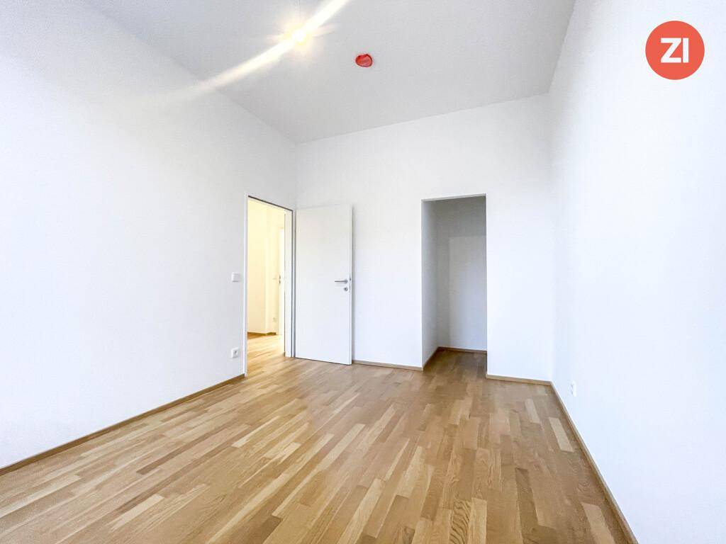 Helles Zimmer mit Holzboden und weiß gestrichenen Wänden, bereit zur individuellen Gestaltung.