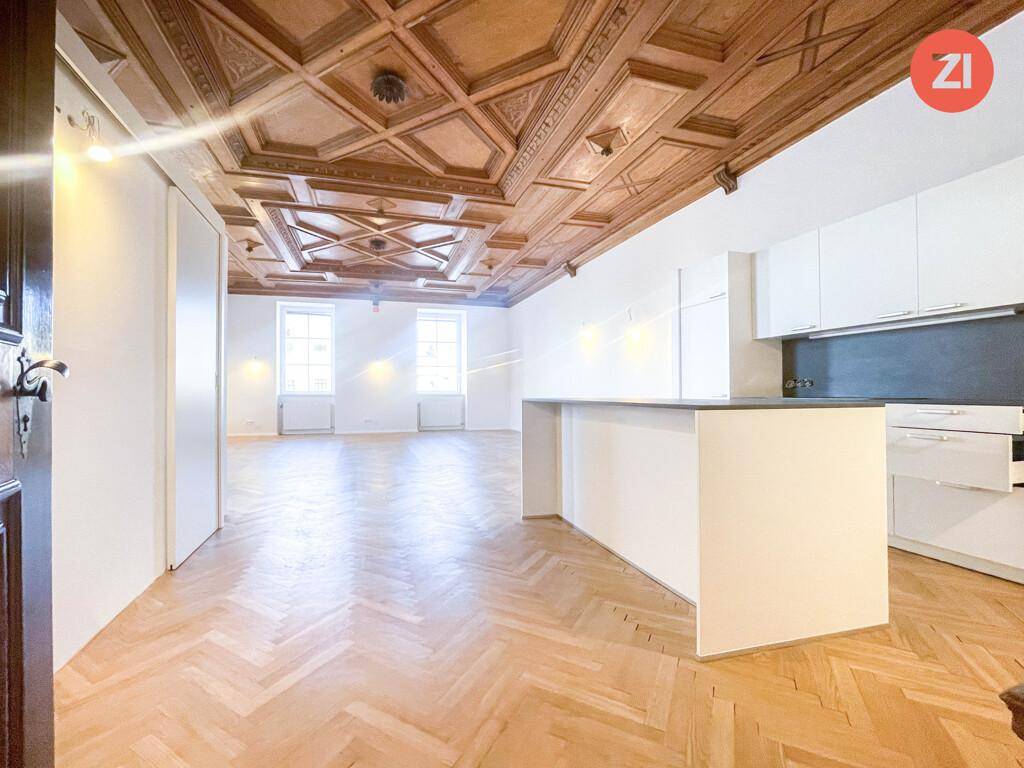 Heller Wohnbereich mit moderner Küchenzeile, Fischgrätparkett und einer beeindruckenden Holzkassettendecke.