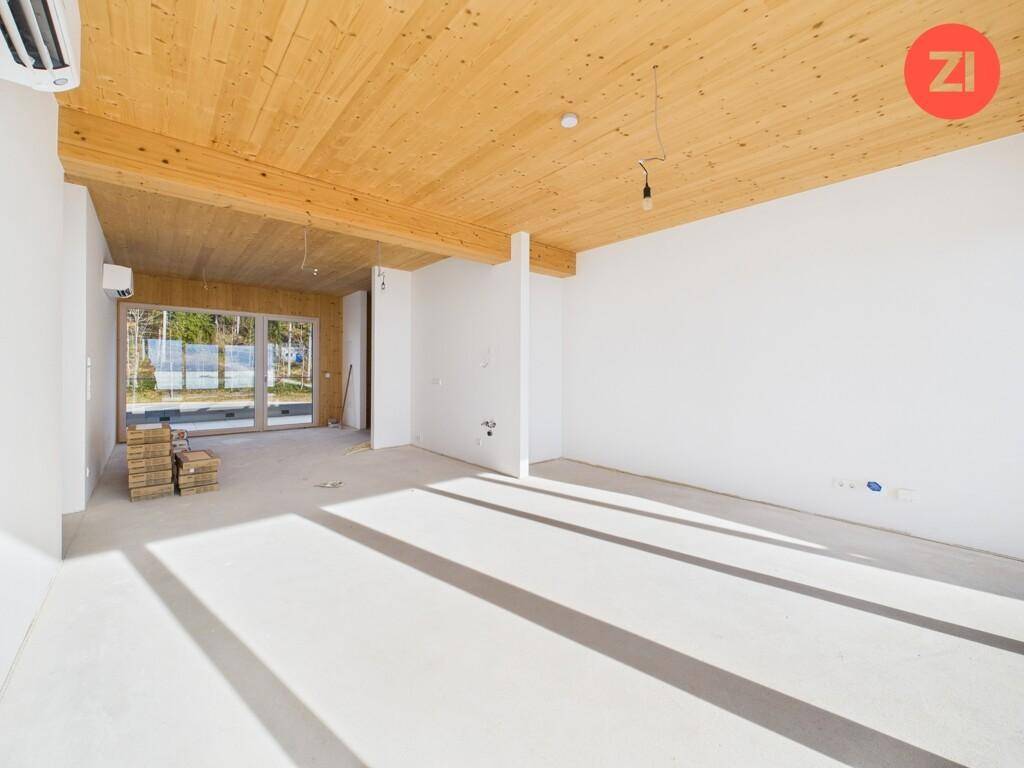 Heller Rohbau mit Holzbalkendecke und Betonboden, bereit für den Innenausbau.