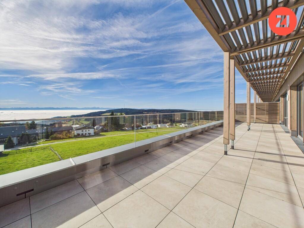 Weitläufige Dachterrasse mit Fliesenboden, Glasgeländer und Panoramablick über die Landschaft.
