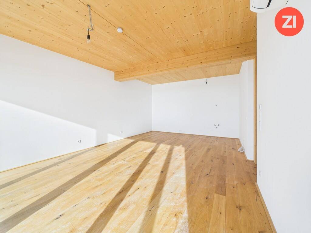 Geräumiger, unmöblierter Raum mit Holzboden und Holzdecke, ideal für individuelle Gestaltung.