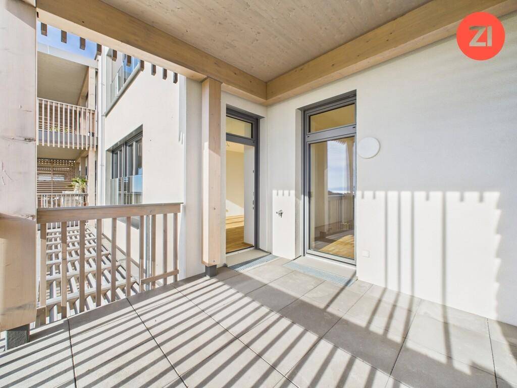 Heller Balkon mit Fliesenboden und Holzgeländer, mit Blick auf die moderne Architektur des Gebäudes.