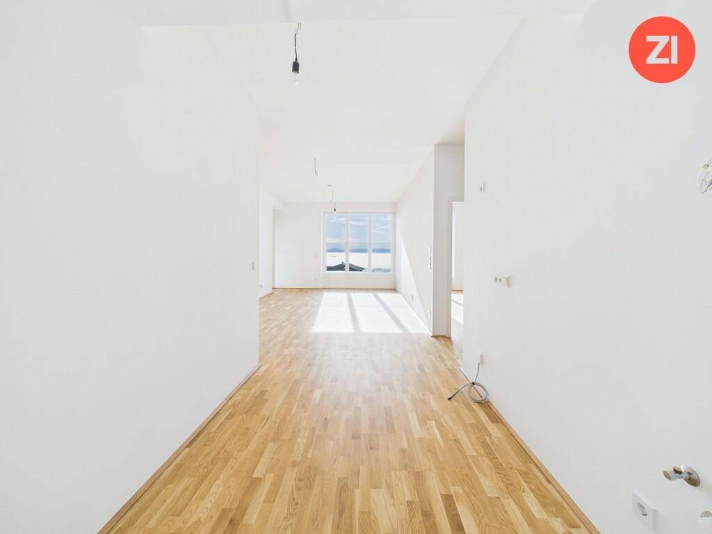 Lichtdurchfluteter Raum mit Holzboden und weitem Panoramablick durch große Fenster.