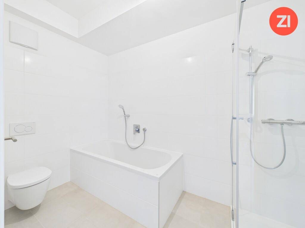 Modernes Badezimmer mit weißen Fliesen, Badewanne, Duschkabine und wandhängendem WC.