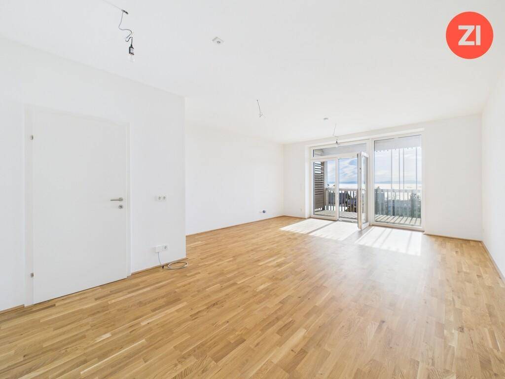 Heller Wohnbereich mit Parkettboden und großen Glastüren, die zu einem Balkon führen.