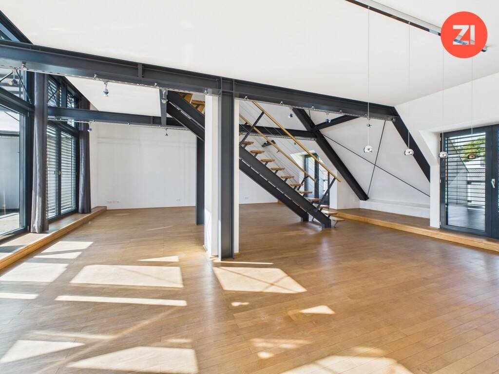 Großzügiger, lichtdurchfluteter Wohnraum mit Holzboden und sichtbaren Stahlträgern.