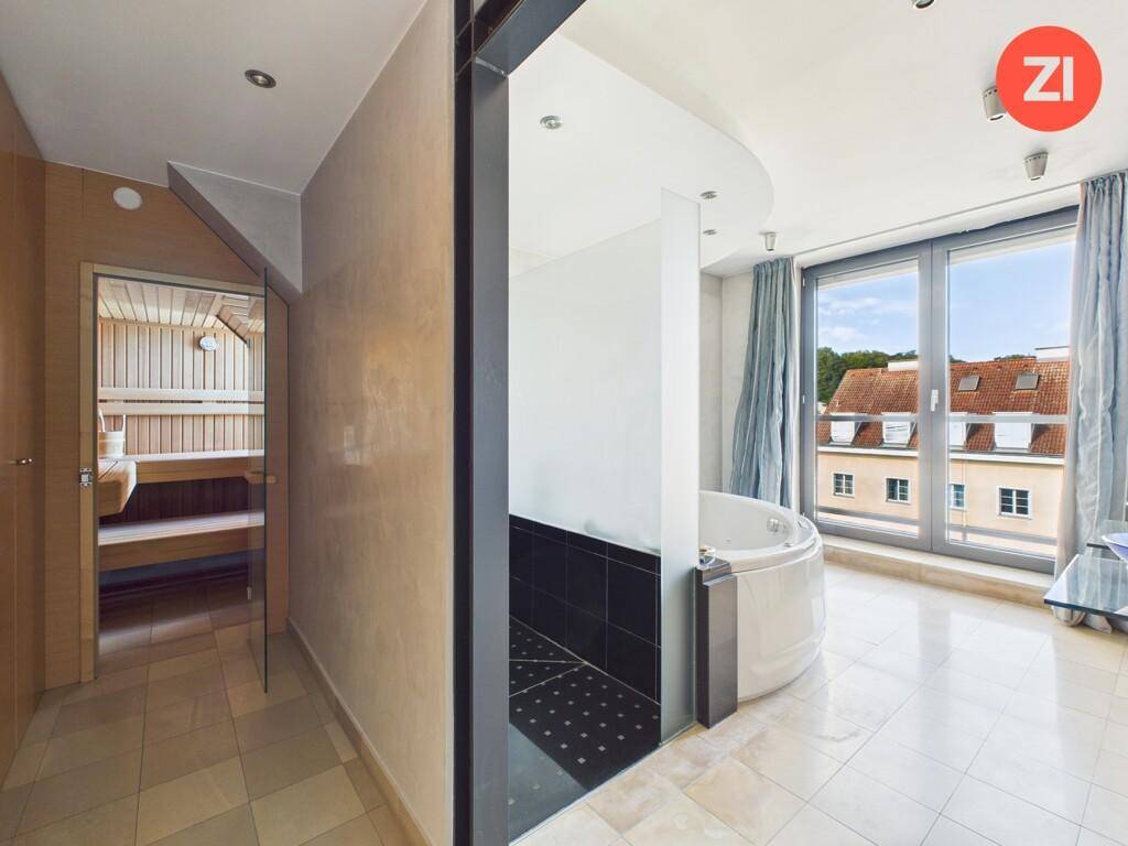 Luxuriöses Badezimmer mit Whirlpool-Badewanne, Sauna und Blick ins Grüne.