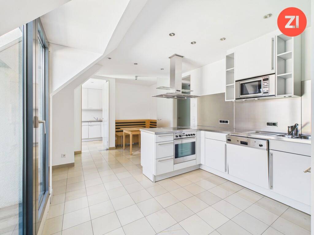 Moderne Einbauküche mit weißen Schränken, Kochinsel und Zugang zur Terrasse.