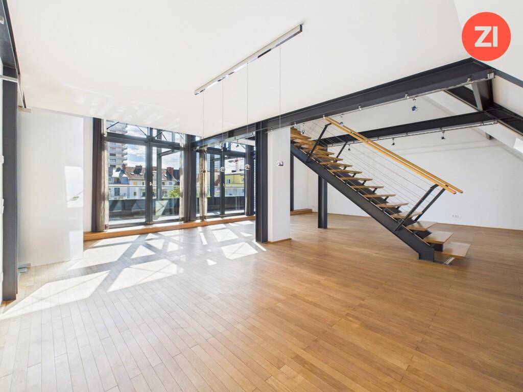 Heller Wohnbereich mit Holzboden, großen Fenstern und moderner offener Treppe.