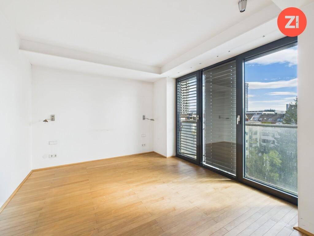 Helles Schlafzimmer mit Holzboden und großen Schiebetüren zum Balkon.