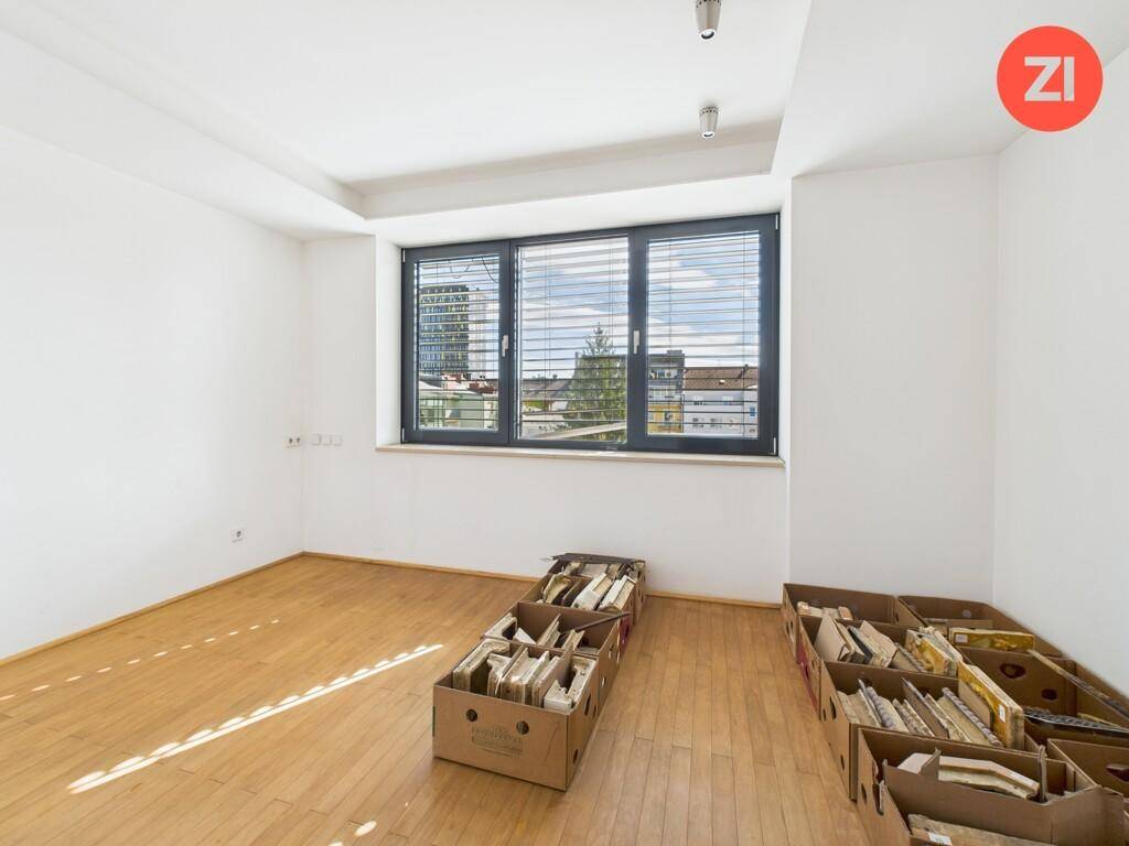 Helles Schlafzimmer mit Holzboden und großem Fenster mit Stadtblick.