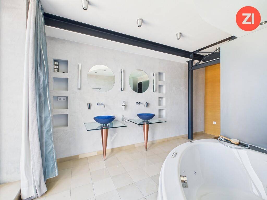 Elegantes Badezimmer mit Doppelwaschbecken, Whirlpool und modernen Armaturen.