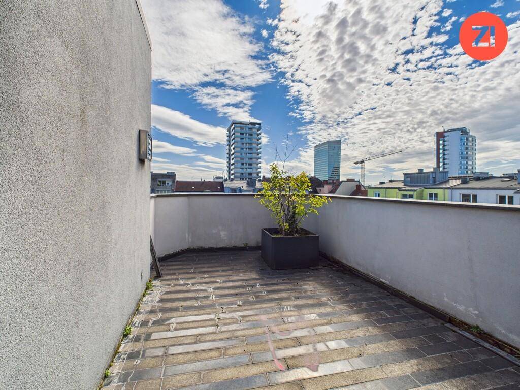 Kleine, sonnige Terrasse mit Stadtblick und Pflanzkübel.
