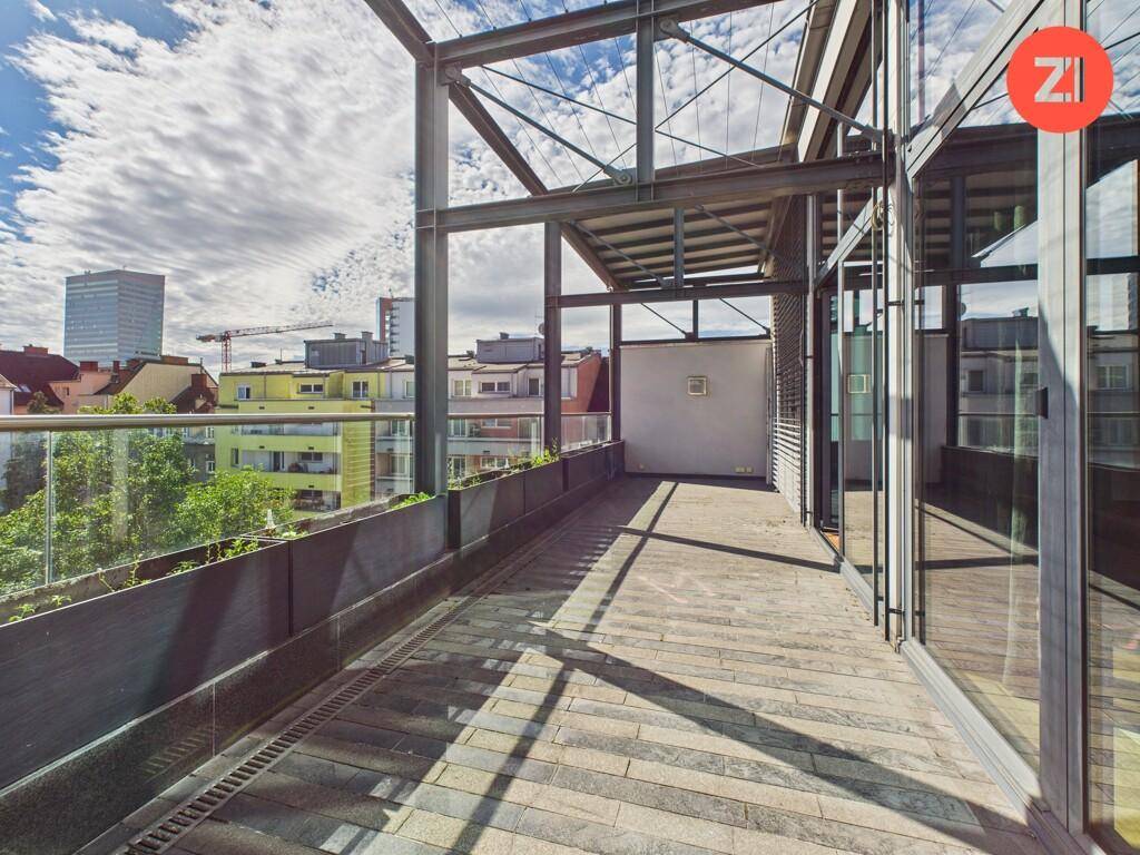 Geräumige Dachterrasse mit Stadtblick und moderner Glasbrüstung.