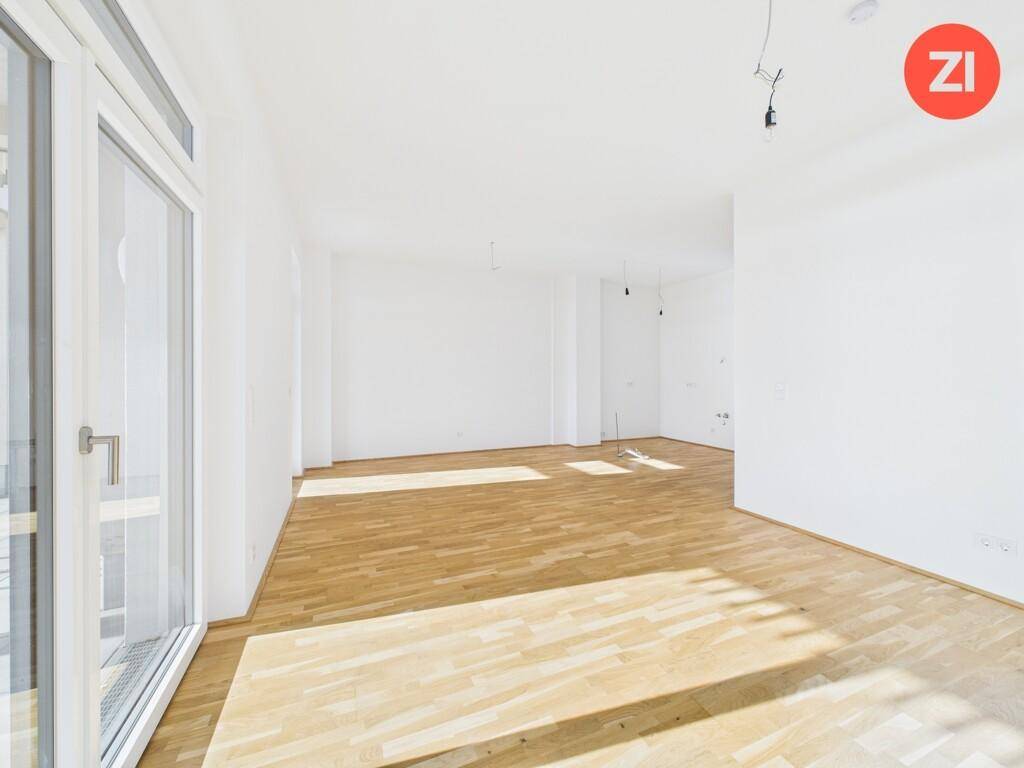 Geräumiges, helles Wohnzimmer mit Holzboden und viel Tageslicht durch große Fenster.