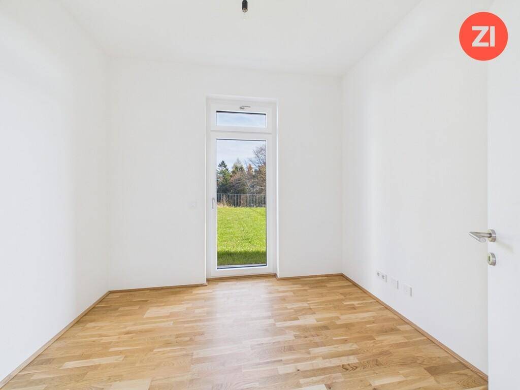 Helles Zimmer mit Parkettboden und Fenster mit Blick ins Grüne, ideal als Schlafzimmer.
