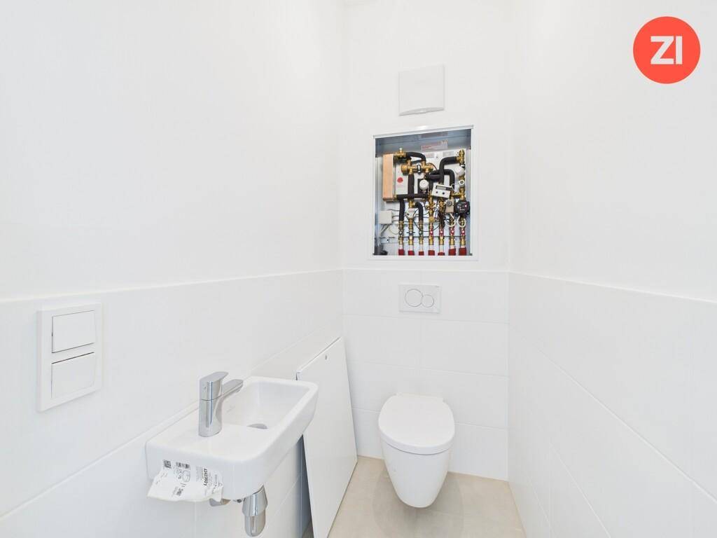 Kleines Gäste-WC mit Waschbecken und wandhängender Toilette, modern gefliest.