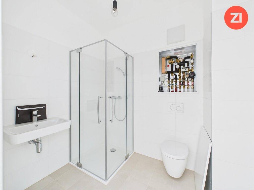 Modernes Badezimmer mit Eckdusche, Waschbecken und WC, in hellen Farben gehalten.