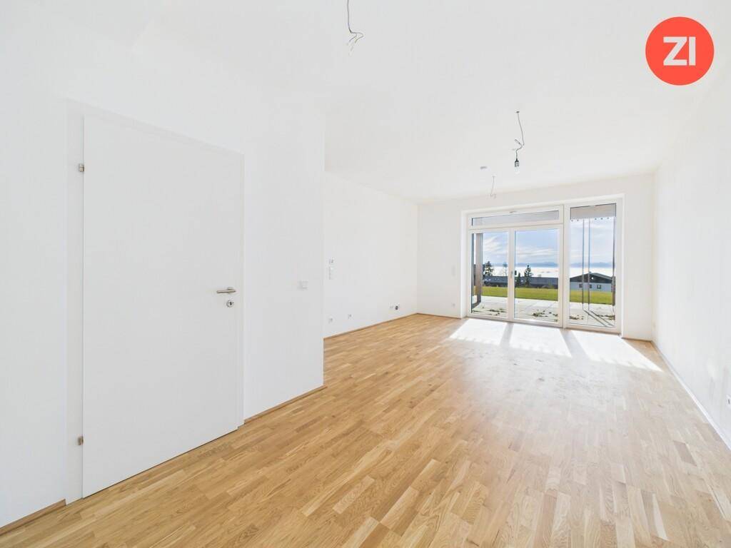 Heller, leerer Wohnraum mit Eichenparkettboden und großen Schiebetüren zur Terrasse mit Weitblick.