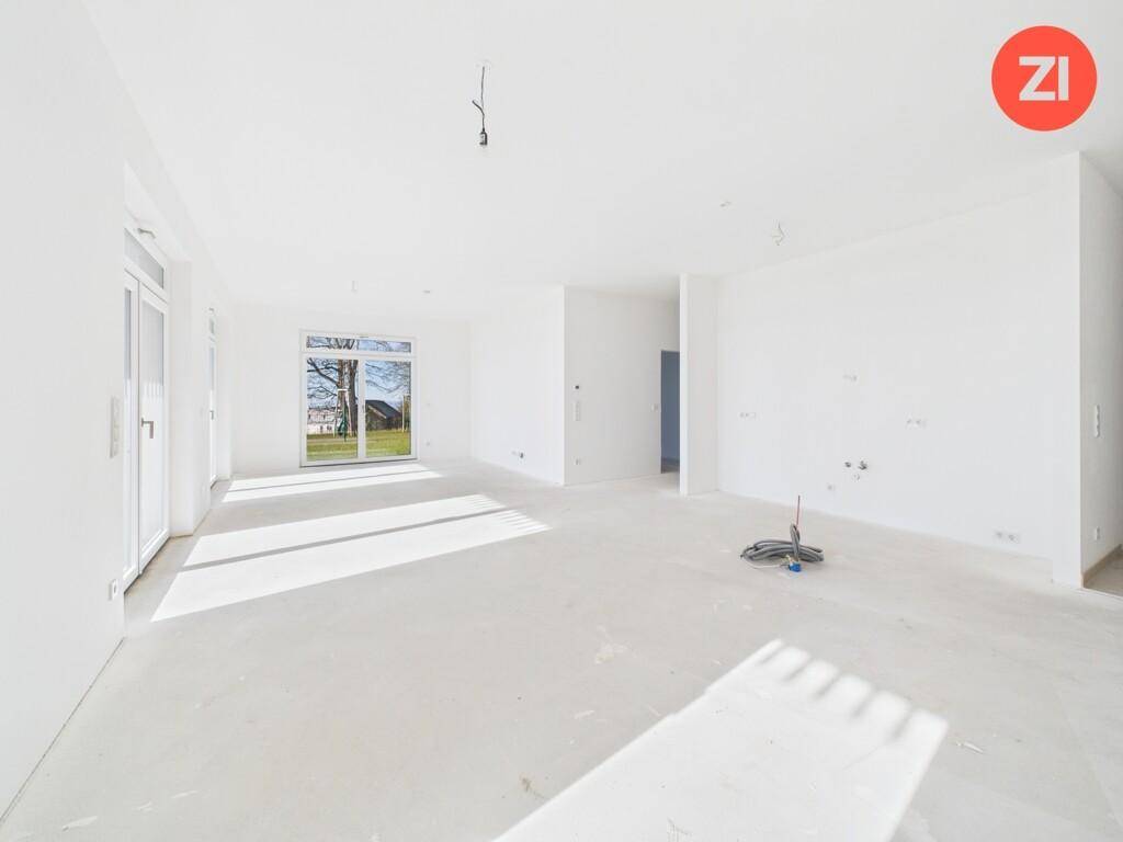 Heller, unmöblierter Wohnbereich im Neubau mit großen Fenstern und viel Tageslicht.