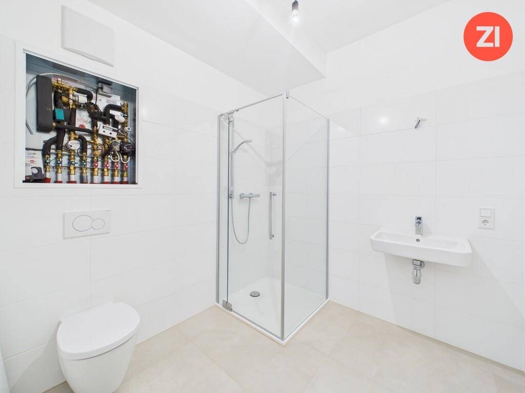 Helles Badezimmer im Neubau mit Duschkabine, WC und Waschbecken, Installationsschacht sichtbar.