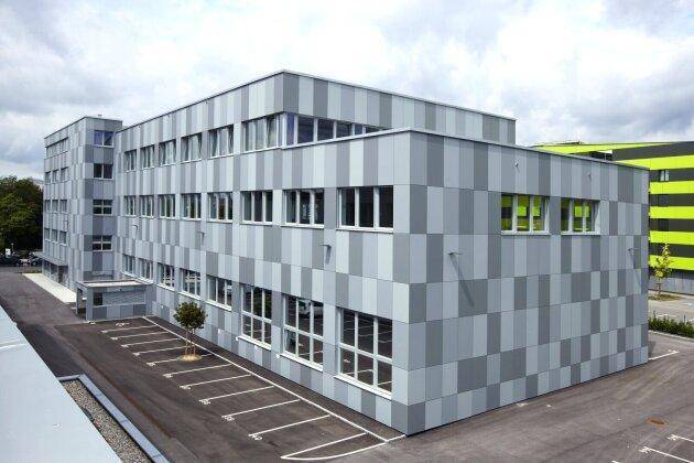 Ansicht des modernen Bürogebäudes von einer anderen Seite mit Parkplätzen und einer auffälligen Fassade.