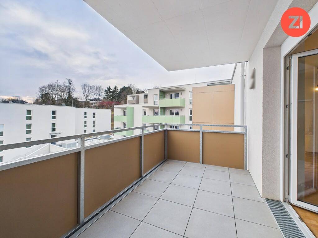 Geräumiger Balkon mit Fliesenboden und Blick auf die umliegenden Wohngebäude.