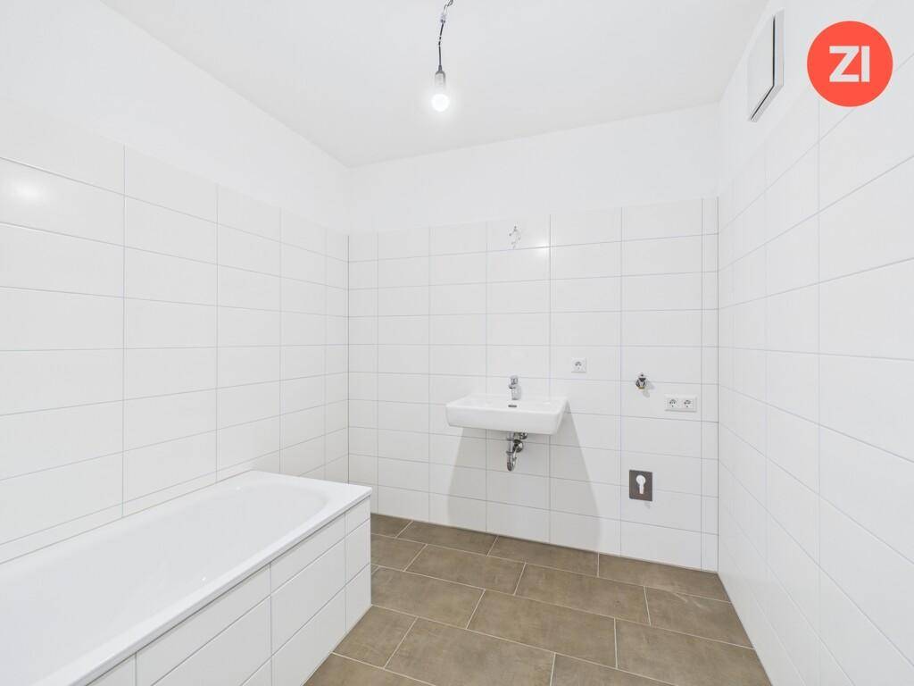 Badezimmer mit weißen Fliesen, Badewanne und Waschbecken, bereit für die Endmontage.