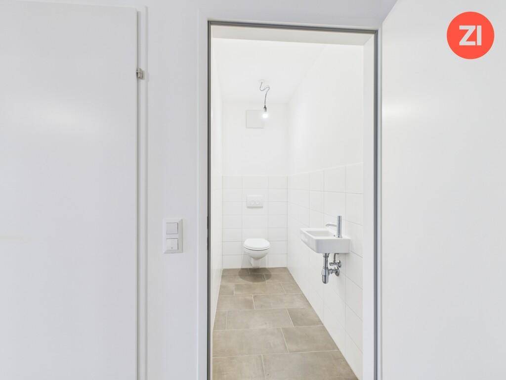 Separates Gäste-WC mit Wand-WC und kleinem Handwaschbecken, modern gefliest.