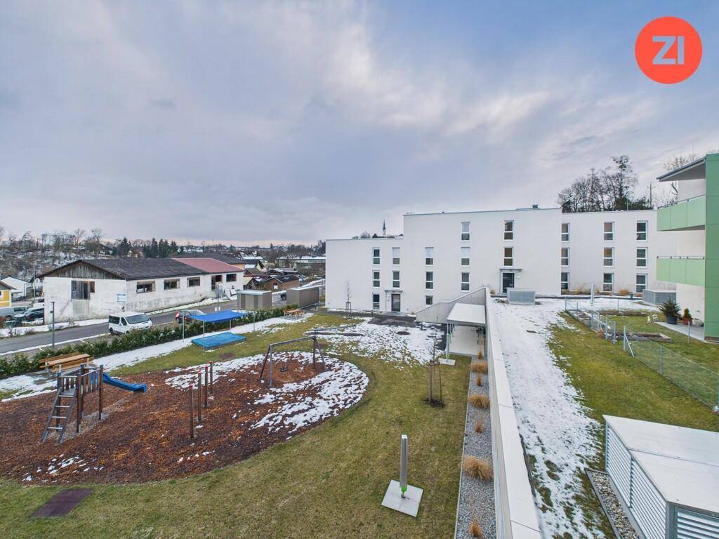 Außenansicht der Wohnanlage mit Spielplatz und umliegender Landschaft im Winter.